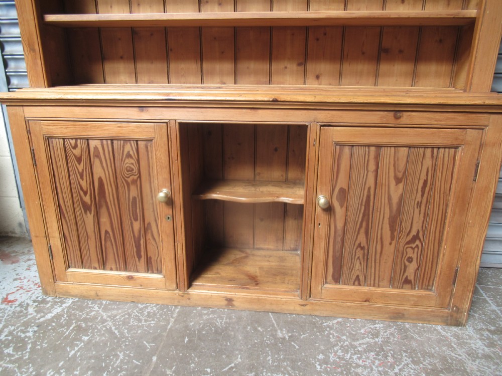 A large Victorian pitch pine kitchen dresser featuring a three-tier open shelf rack positioned above a base unit with two panelled doors and an open central alcove. View IX