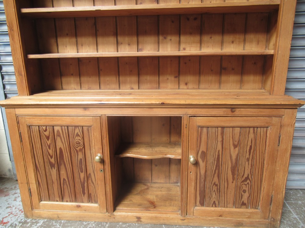 A large Victorian pitch pine kitchen dresser featuring a three-tier open shelf rack positioned above a base unit with two panelled doors and an open central alcove. View X