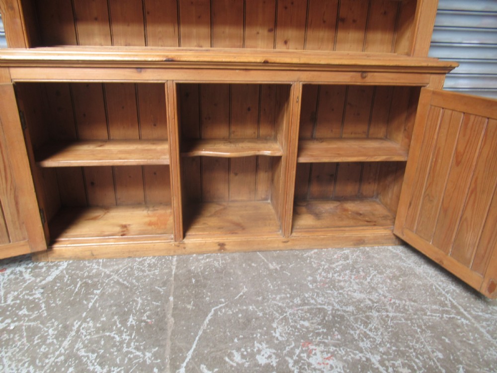 A large Victorian pitch pine kitchen dresser featuring a three-tier open shelf rack positioned above a base unit with two panelled doors and an open central alcove. View XI
