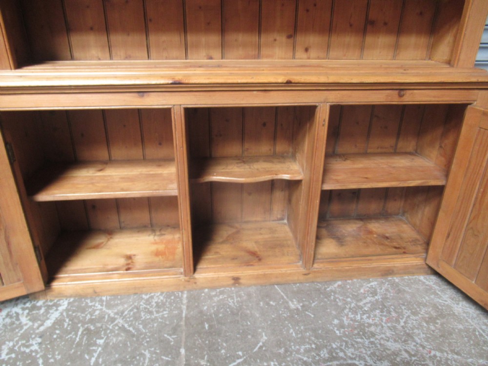 A large Victorian pitch pine kitchen dresser featuring a three-tier open shelf rack positioned above a base unit with two panelled doors and an open central alcove. View XII