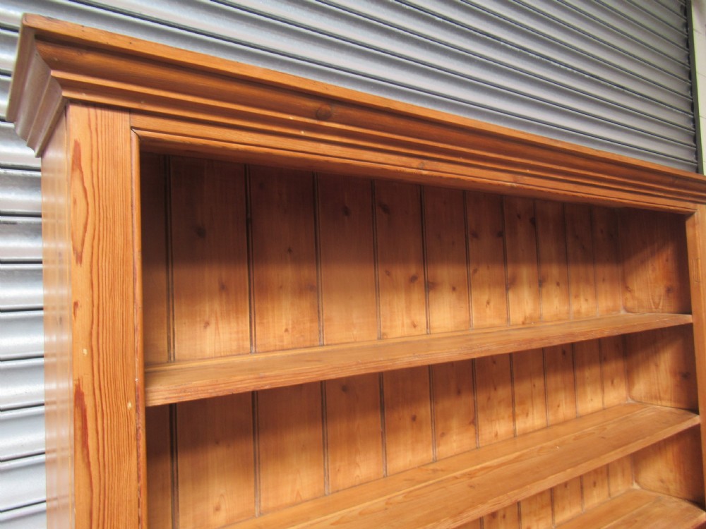 A large Victorian pitch pine kitchen dresser featuring a three-tier open shelf rack positioned above a base unit with two panelled doors and an open central alcove. View XIII