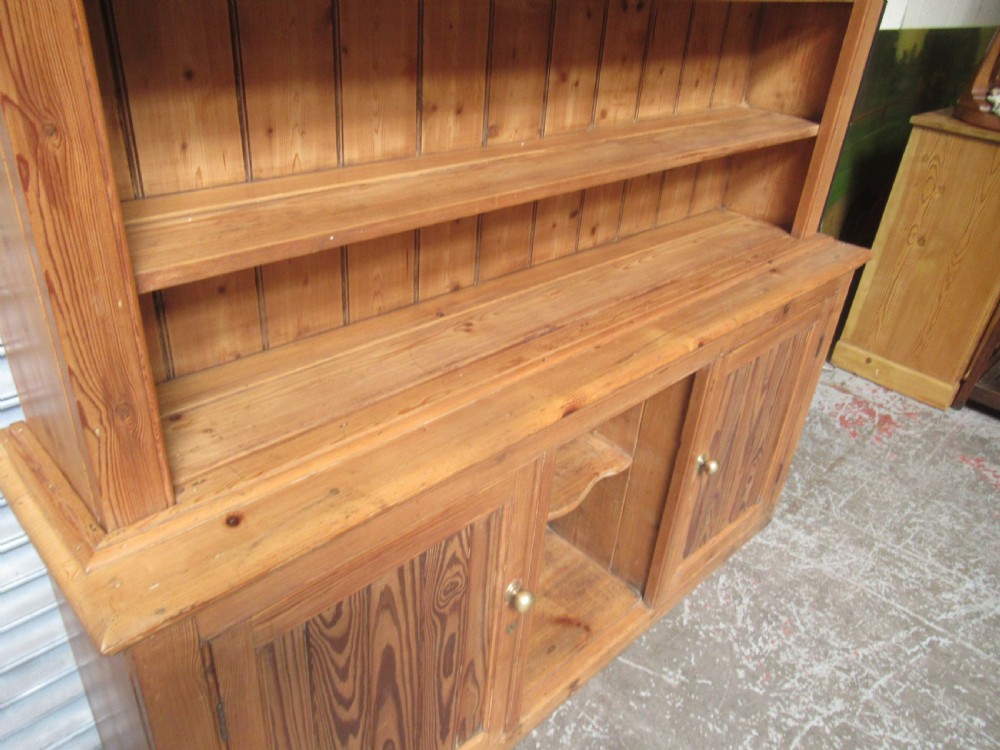 A large Victorian pitch pine kitchen dresser featuring a three-tier open shelf rack positioned above a base unit with two panelled doors and an open central alcove. View XIV