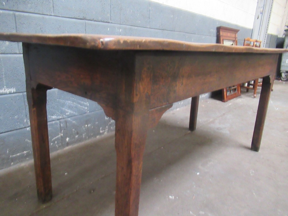 An early 19th-century wooden dining table featuring a rectangular planked top and four sturdy tapering legs. View V