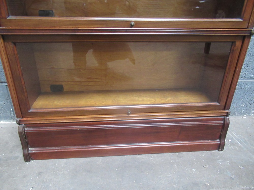 A five-tier mahogany sectional bookcase featuring glazed lift-up doors with small brass knobs and a moulded top cornice. View VI