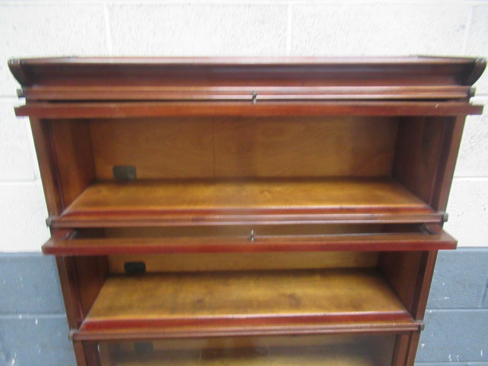 A five-tier mahogany sectional bookcase featuring glazed lift-up doors with small brass knobs and a moulded top cornice. View VIII