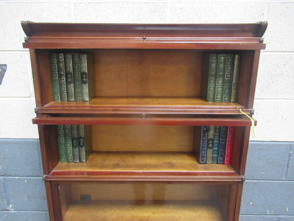 A five-tier mahogany sectional bookcase featuring glazed lift-up doors with small brass knobs and a moulded top cornice. View IX