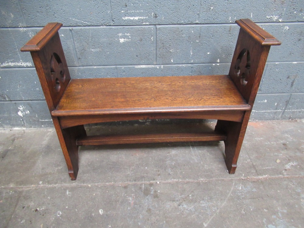 A solid oak Arts and Crafts bench seat with raised side uprights featuring pierced trefoil cutouts. View II