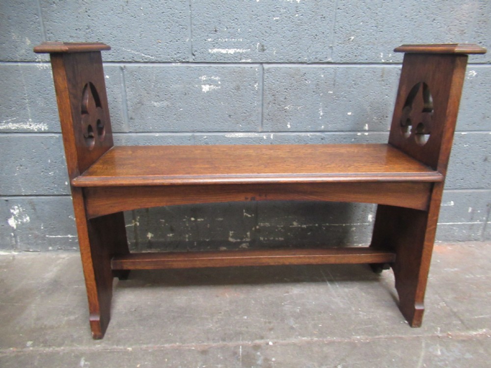 A solid oak Arts and Crafts bench seat with raised side uprights featuring pierced trefoil cutouts. View III