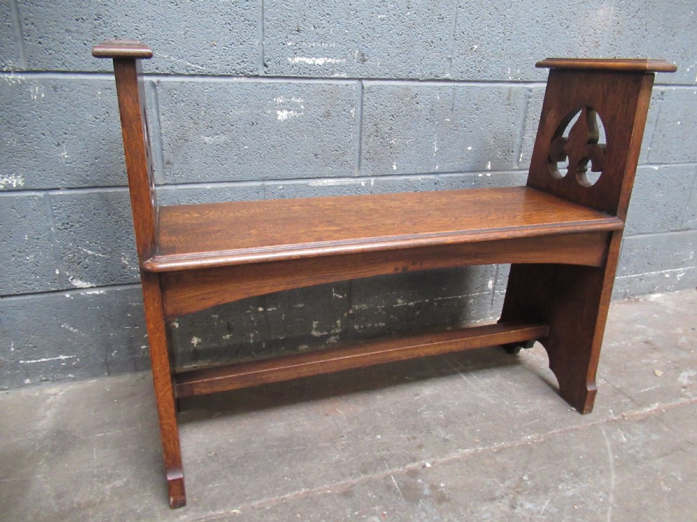 A solid oak Arts and Crafts bench seat with raised side uprights featuring pierced trefoil cutouts. View V