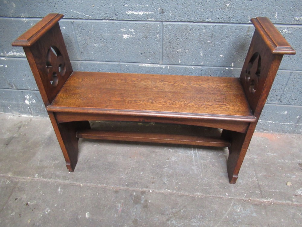 A solid oak Arts and Crafts bench seat with raised side uprights featuring pierced trefoil cutouts. View IX