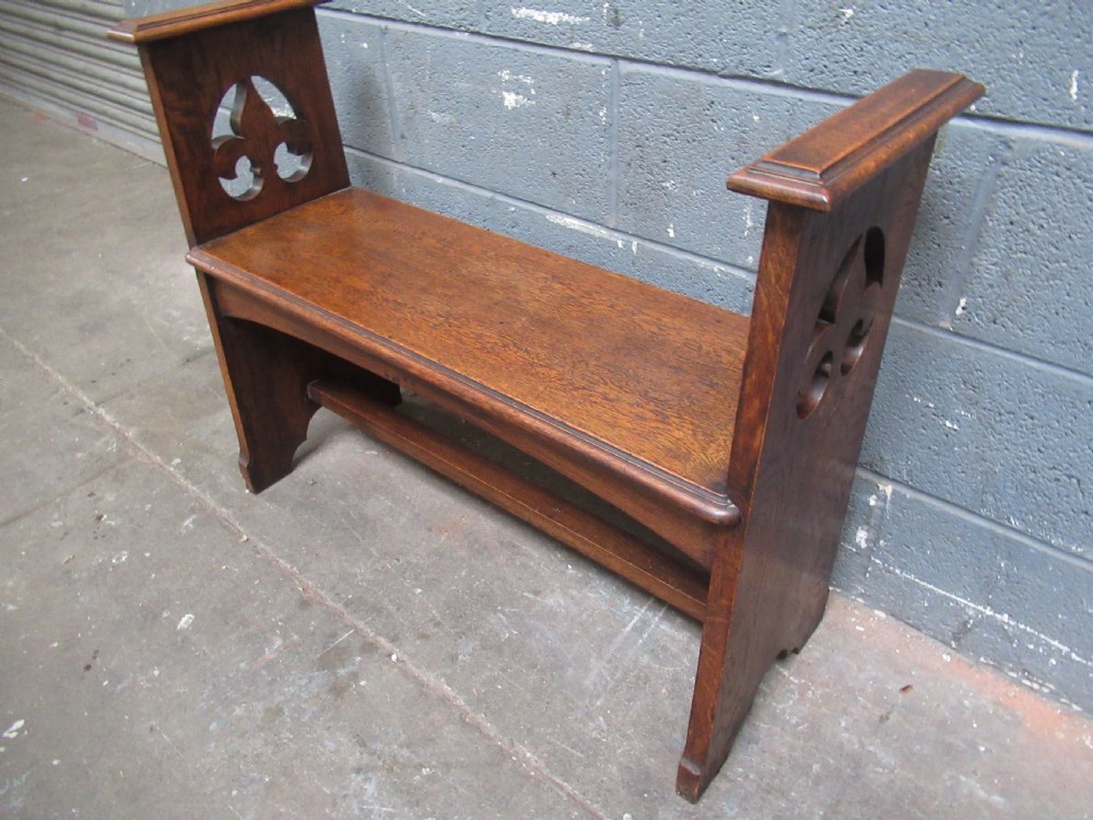 A solid oak Arts and Crafts bench seat with raised side uprights featuring pierced trefoil cutouts. View X