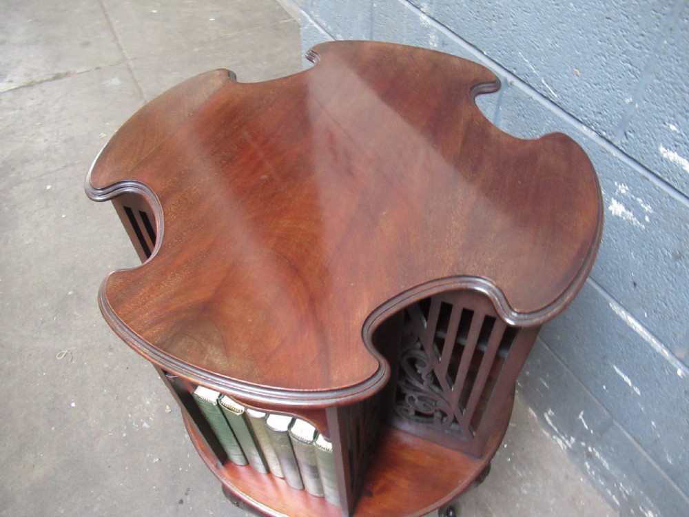 A late Victorian dark mahogany revolving bookcase featuring open compartments with carved fretwork side panels, raised on four slender cabriole legs. View V
