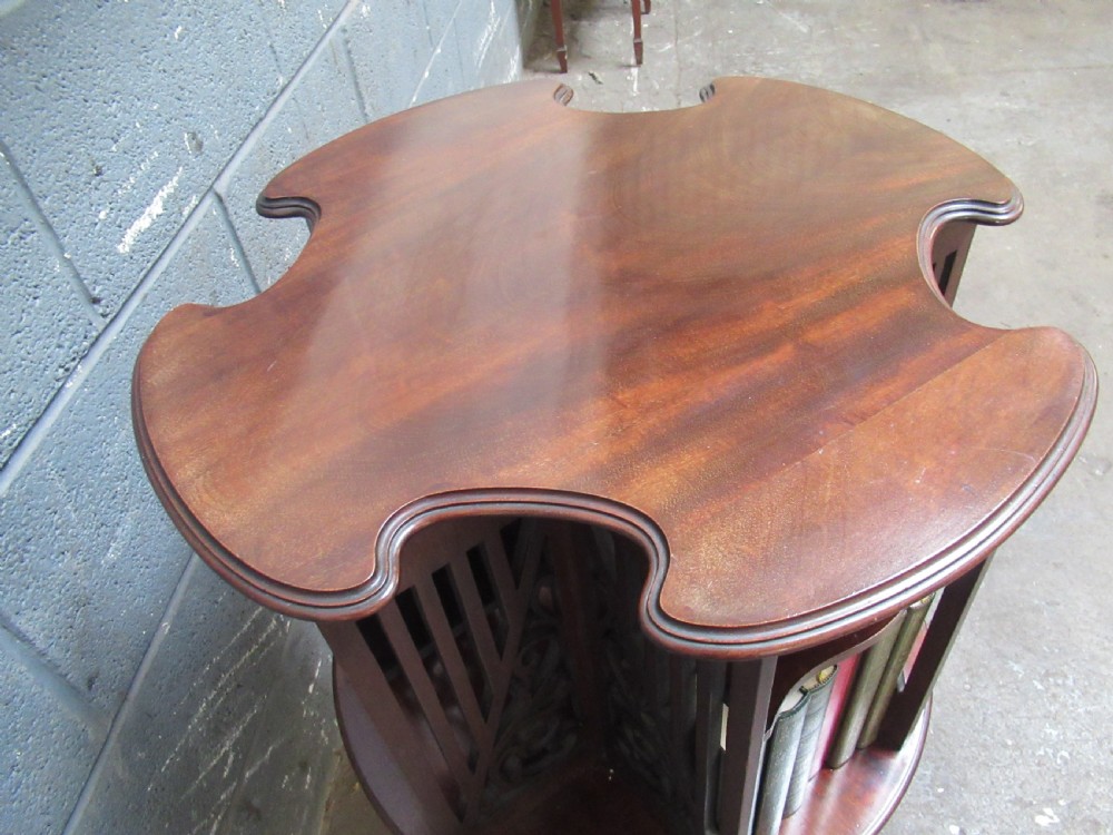 A late Victorian dark mahogany revolving bookcase featuring open compartments with carved fretwork side panels, raised on four slender cabriole legs. View VI