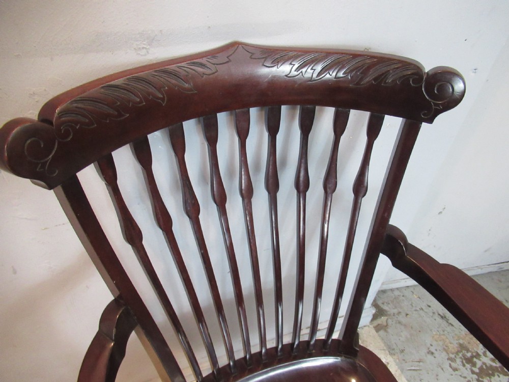 An Edwardian dark mahogany armchair featuring a carved top rail, spindle backrest, curved arms, and a solid wooden seat. View III