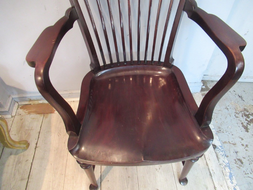 An Edwardian dark mahogany armchair featuring a carved top rail, spindle backrest, curved arms, and a solid wooden seat. View V