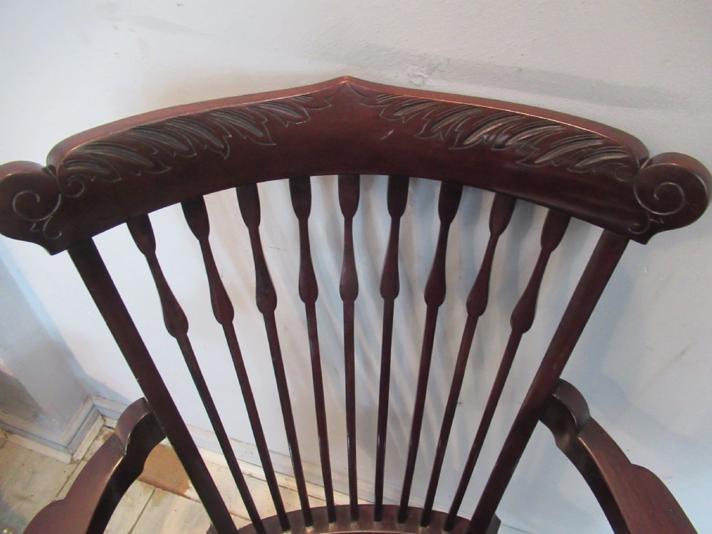 An Edwardian dark mahogany armchair featuring a carved top rail, spindle backrest, curved arms, and a solid wooden seat. View XI