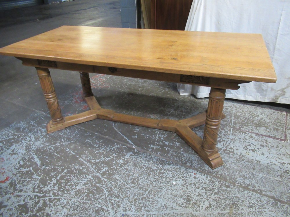 A rectangular light oak refectory dining table featuring carved aprons, spiral turned legs, and a low H-shaped stretcher base.