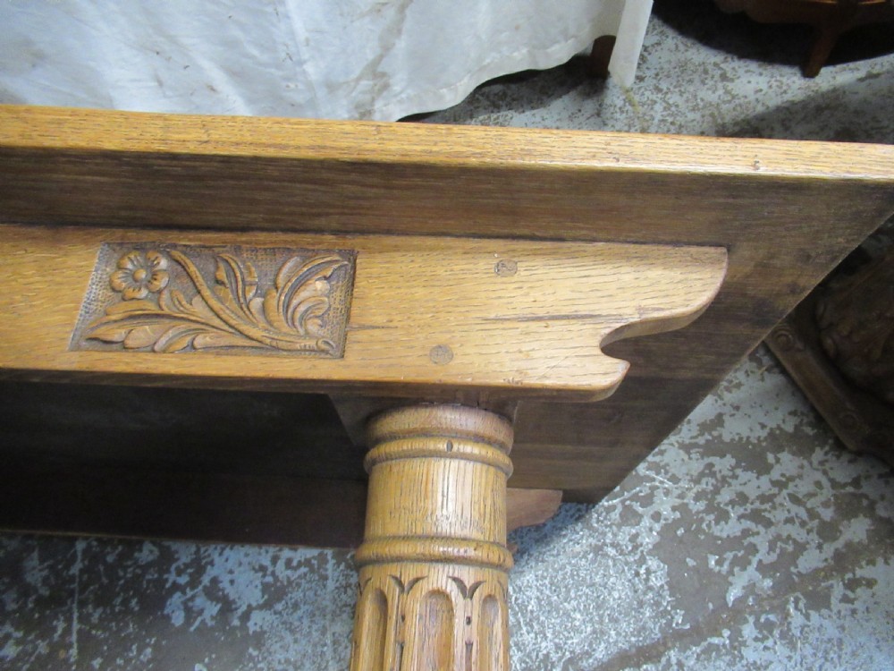 A rectangular light oak refectory dining table featuring carved aprons, spiral turned legs, and a low H-shaped stretcher base. View VII