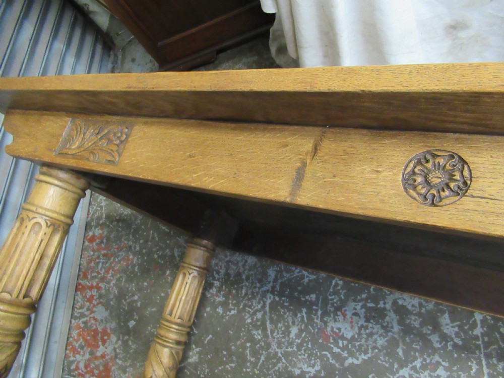 A rectangular light oak refectory dining table featuring carved aprons, spiral turned legs, and a low H-shaped stretcher base. View VIII
