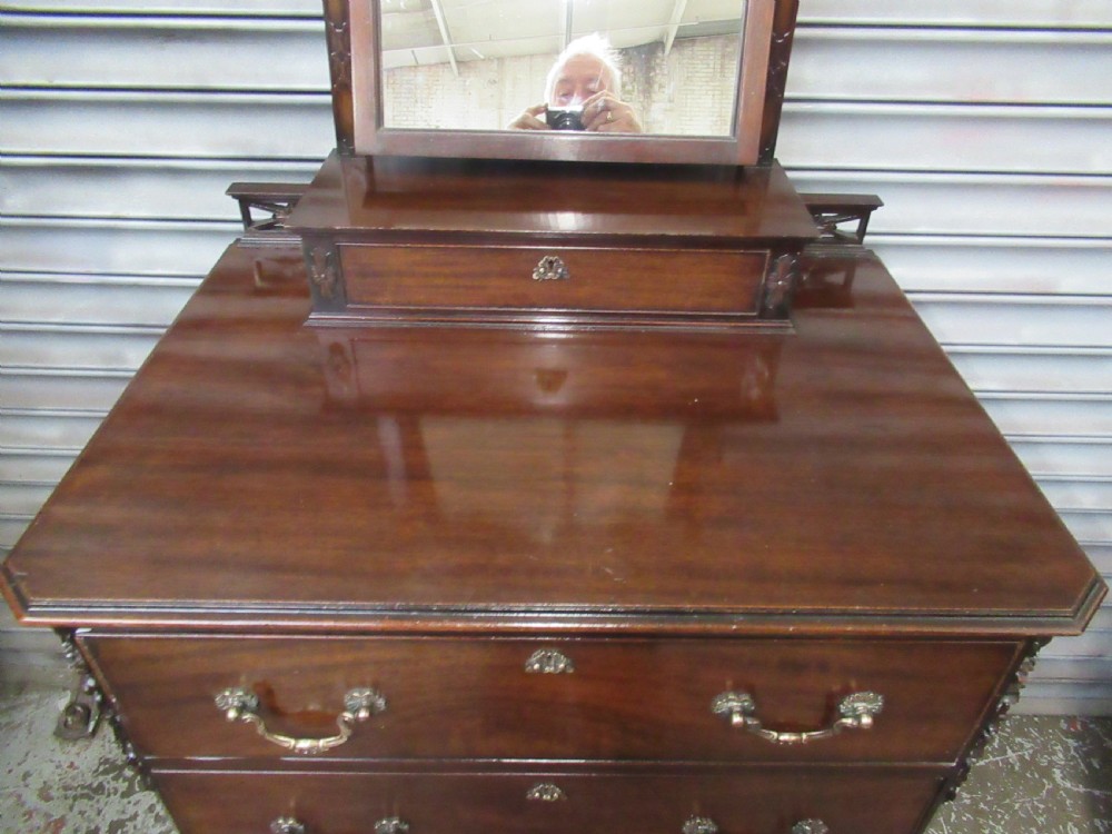 A dark mahogany Chippendale style dressing chest featuring four graduated drawers, brass handles, bracket feet, and a central arch-topped swing mirror. View XII