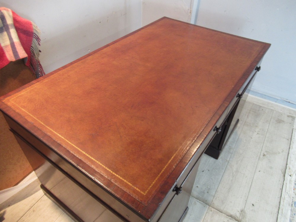 A 19th-century mahogany kneehole desk featuring a leather inset writing surface, two frieze drawers with turned wooden knobs, and two side pedestal cupboards. View II