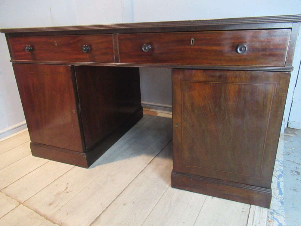 A 19th-century mahogany kneehole desk featuring a leather inset writing surface, two frieze drawers with turned wooden knobs, and two side pedestal cupboards. View VI