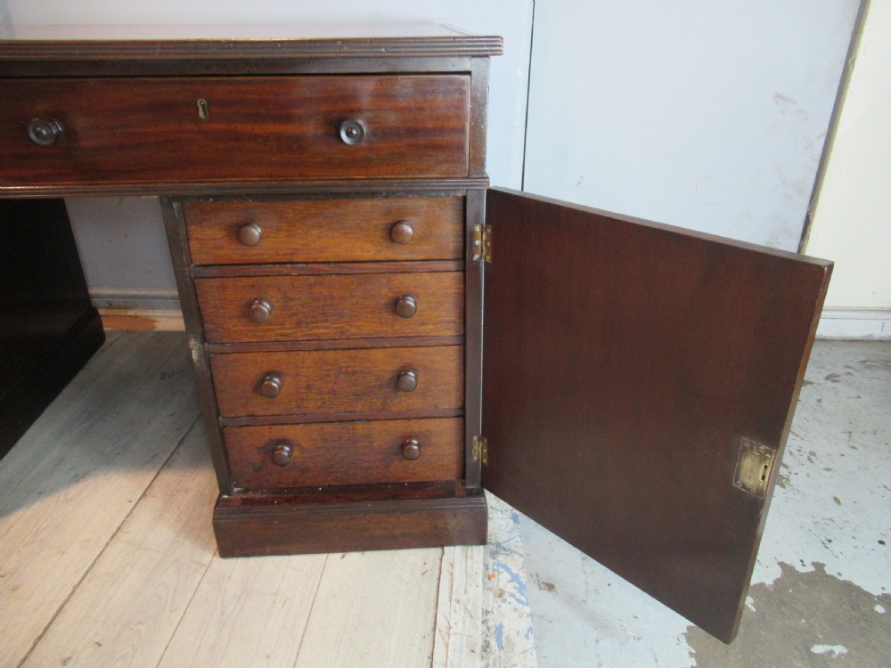 A 19th-century mahogany kneehole desk featuring a leather inset writing surface, two frieze drawers with turned wooden knobs, and two side pedestal cupboards. View VII