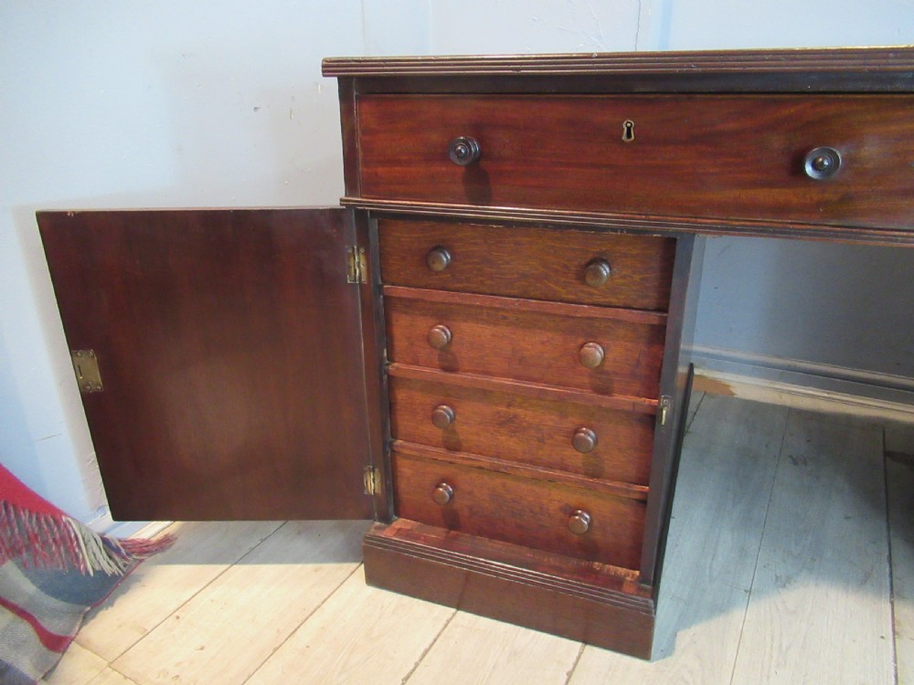 A 19th-century mahogany kneehole desk featuring a leather inset writing surface, two frieze drawers with turned wooden knobs, and two side pedestal cupboards. View VIII