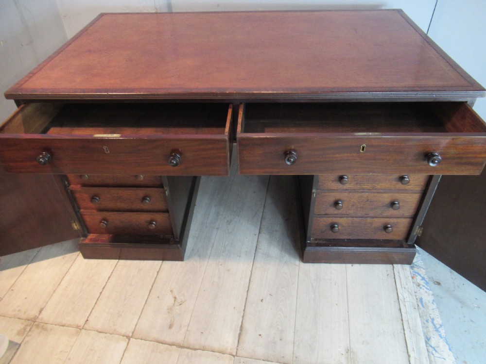 A 19th-century mahogany kneehole desk featuring a leather inset writing surface, two frieze drawers with turned wooden knobs, and two side pedestal cupboards. View IX