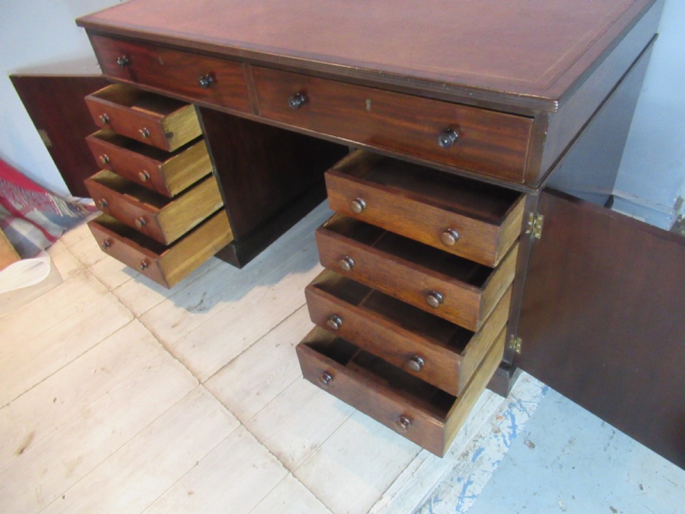 A 19th-century mahogany kneehole desk featuring a leather inset writing surface, two frieze drawers with turned wooden knobs, and two side pedestal cupboards. View XII