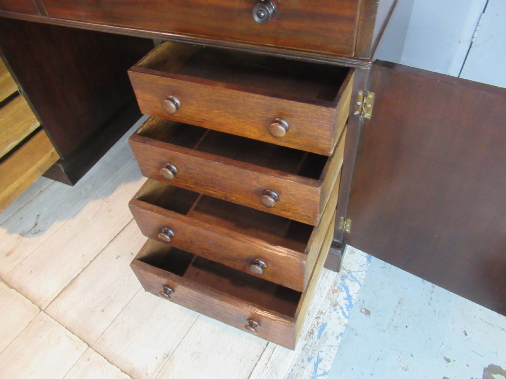 A 19th-century mahogany kneehole desk featuring a leather inset writing surface, two frieze drawers with turned wooden knobs, and two side pedestal cupboards. View XIII