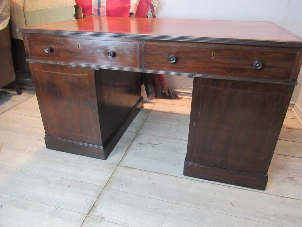 A 19th-century mahogany kneehole desk featuring a leather inset writing surface, two frieze drawers with turned wooden knobs, and two side pedestal cupboards. View XV