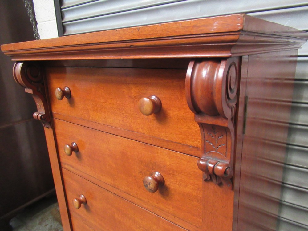 A tall Victorian mahogany Wellington chest featuring seven graduated drawers with turned wooden knobs and carved upper corbels. View VI