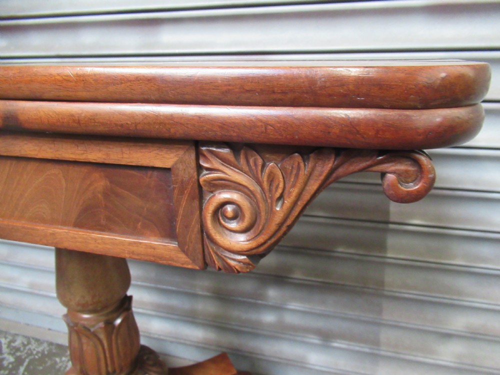Victorian mahogany fold-over tea table featuring a rectangular swivel top, carved scroll frieze details, a central turned column, and a quadruped base with scroll feet. View IV