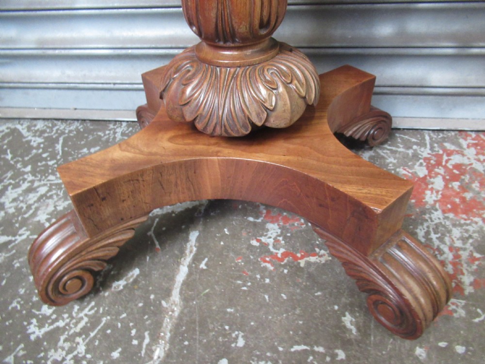 Victorian mahogany fold-over tea table featuring a rectangular swivel top, carved scroll frieze details, a central turned column, and a quadruped base with scroll feet. View V
