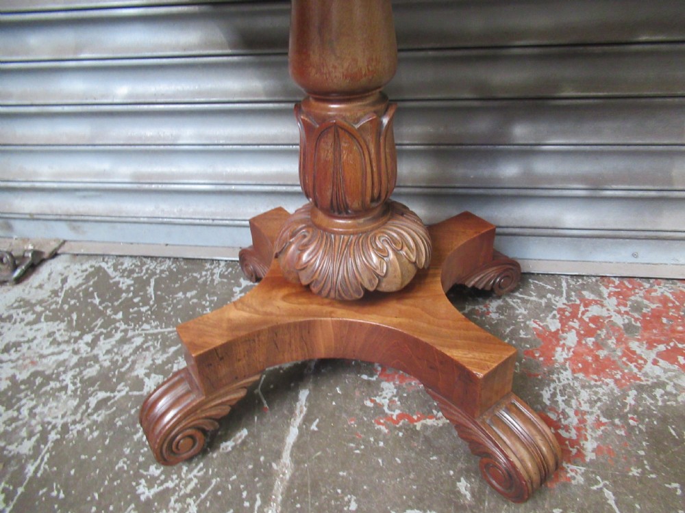 Victorian mahogany fold-over tea table featuring a rectangular swivel top, carved scroll frieze details, a central turned column, and a quadruped base with scroll feet. View VI