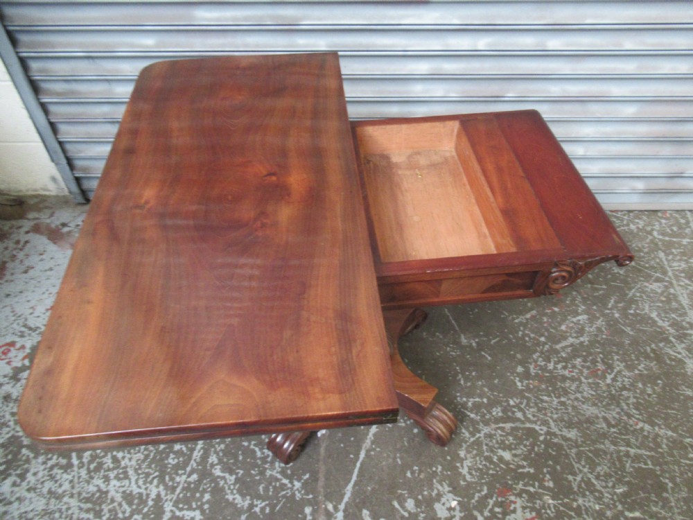 Victorian mahogany fold-over tea table featuring a rectangular swivel top, carved scroll frieze details, a central turned column, and a quadruped base with scroll feet. View VIII