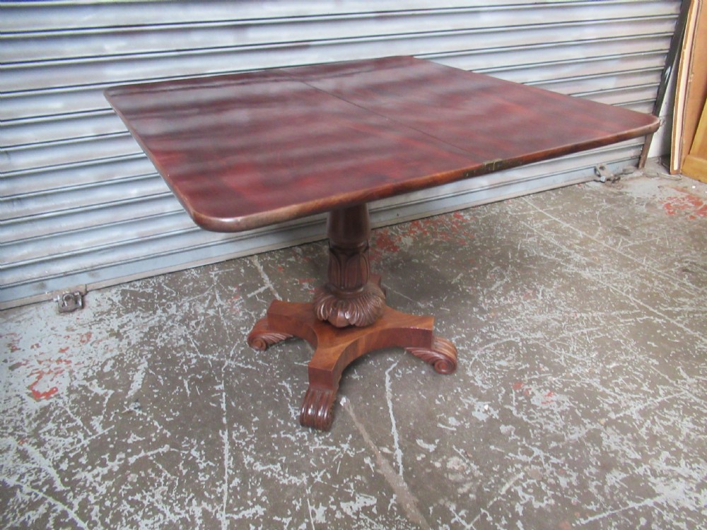 Victorian mahogany fold-over tea table featuring a rectangular swivel top, carved scroll frieze details, a central turned column, and a quadruped base with scroll feet. View X