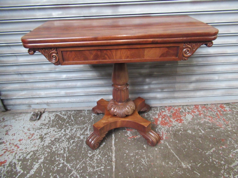 Victorian mahogany fold-over tea table featuring a rectangular swivel top, carved scroll frieze details, a central turned column, and a quadruped base with scroll feet. View XI
