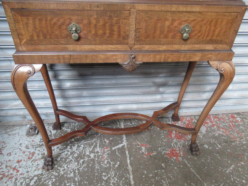 A 1930s mahogany cocktail cabinet on a stand featuring two upper doors with ornate brass strap hinges, lower drawers, cabriole legs, and claw and ball feet. View VI
