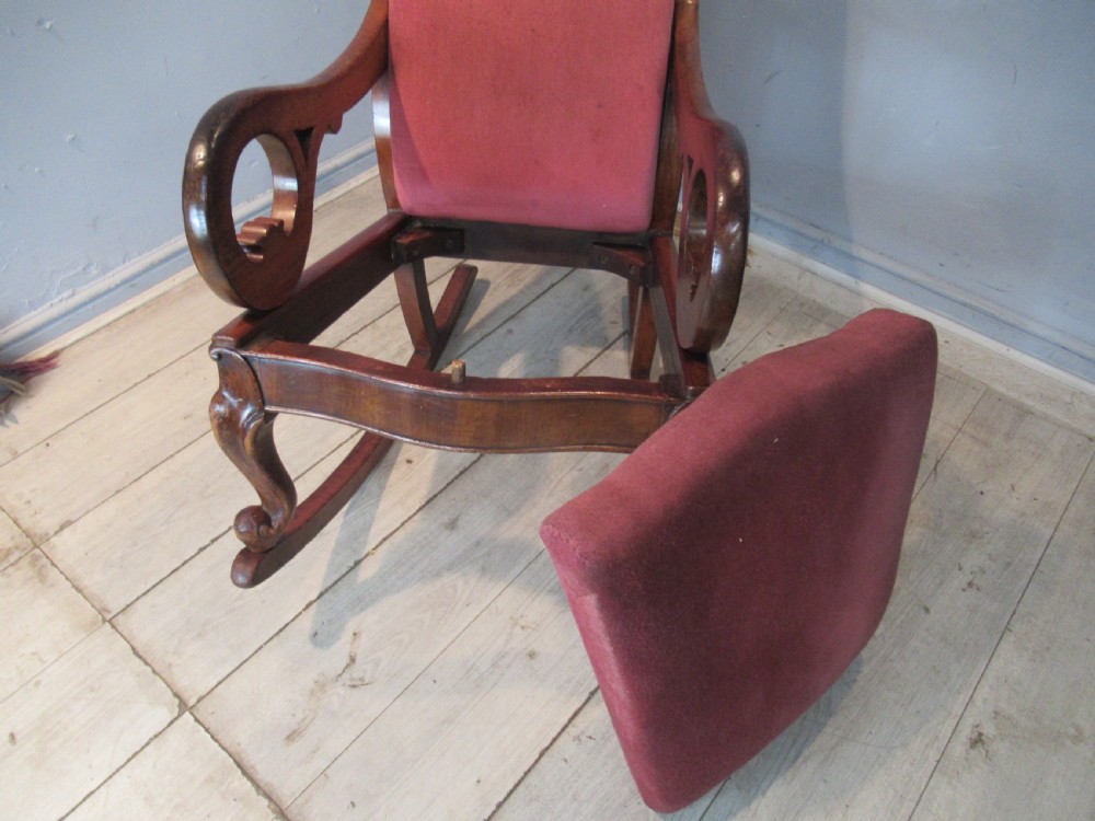A Victorian mahogany rocking chair featuring carved scroll arms and dusty pink upholstery on curved wooden runners. View VIII
