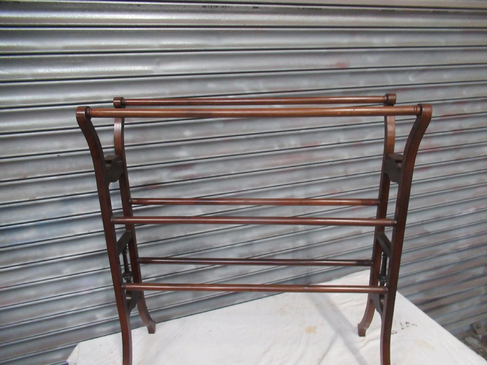 An Edwardian freestanding mahogany towel rail featuring curved top rail supports, carved rosette side mounts, turned central spindles, and splayed feet. View V