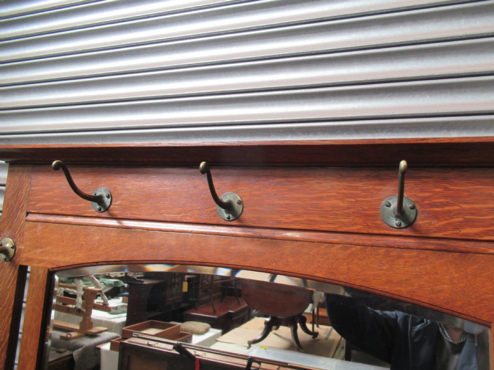 A tall Edwardian oak hall stand featuring an upper mirror, brass hanging hooks, a central glove box shelf, and a lower umbrella stand with metal drip trays. View III