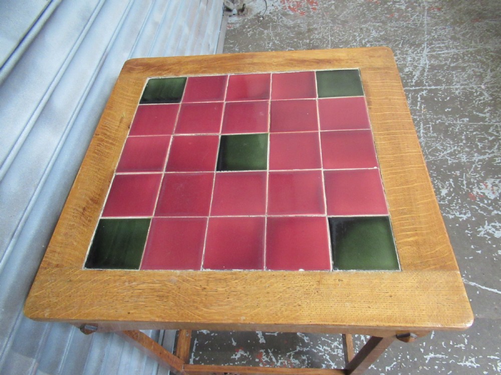 An Arts and Crafts oak side table with a square red and green glazed ceramic tile top, raised on splayed legs with pierced stretchers. View IV