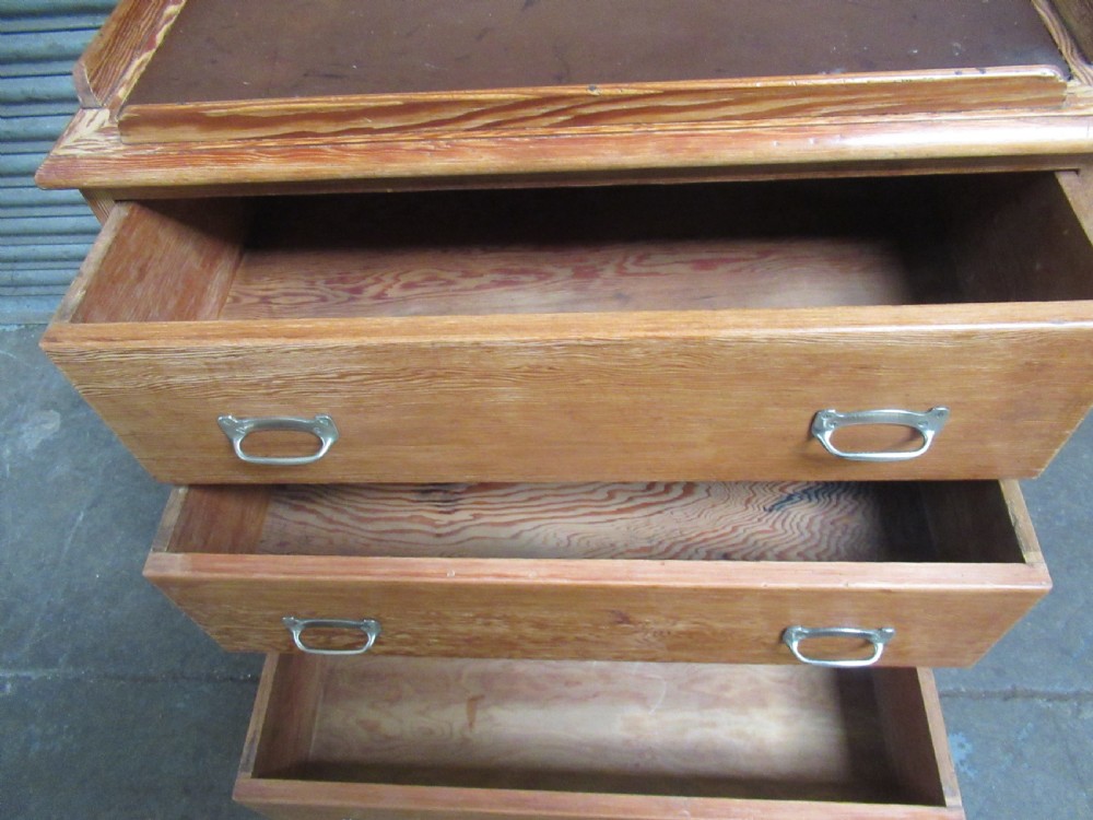 A pitch pine maritime chest of drawers featuring four drawers with flush metal handles and a raised gallery rim at the top. View IX