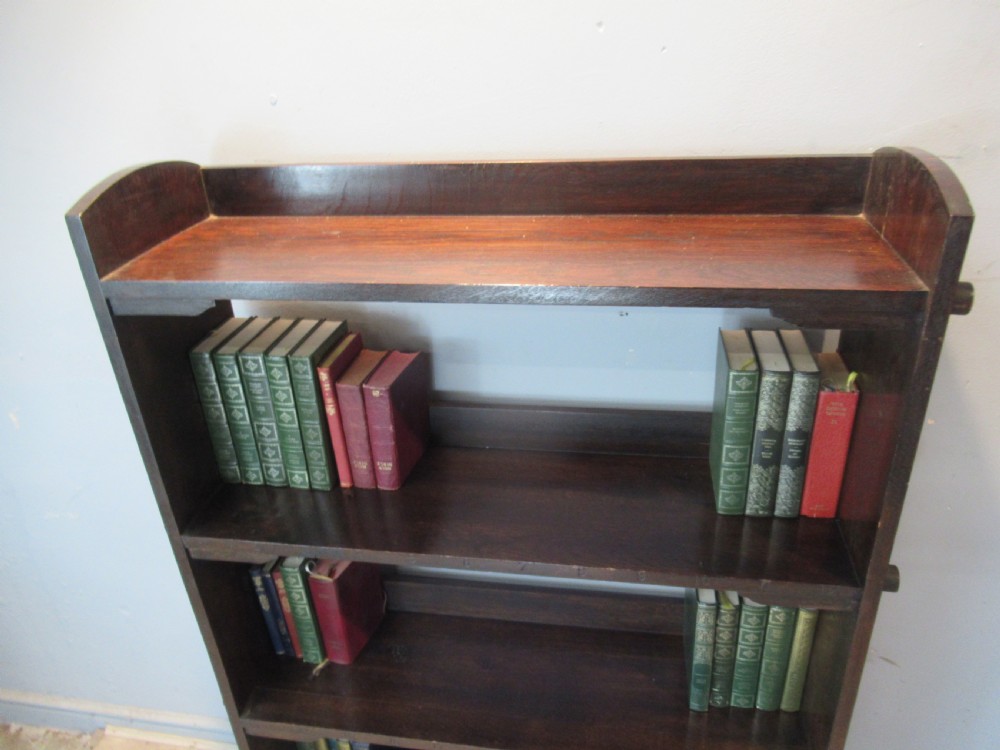 A dark brown solid oak open bookcase featuring four shelves and exposed wedge peg joinery on the side panels. View III