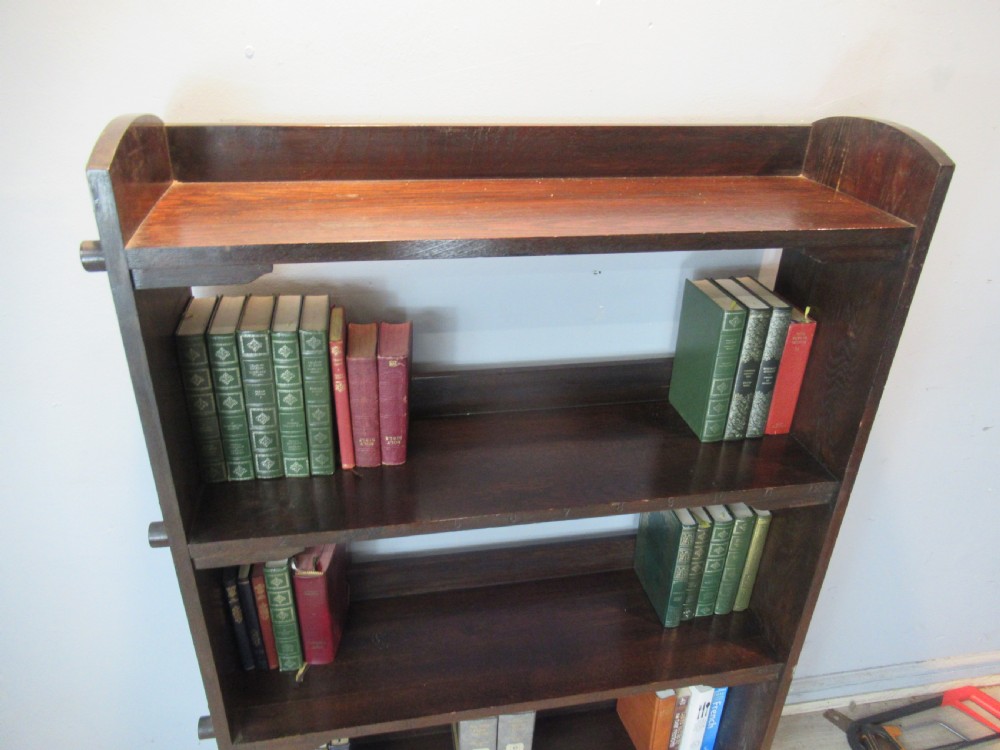 A dark brown solid oak open bookcase featuring four shelves and exposed wedge peg joinery on the side panels. View VII