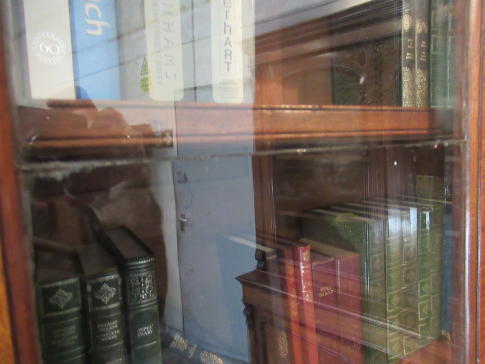 An early nineteenth-century mahogany glazed cupboard bookcase featuring a carved pediment top, two upper glass doors, and two lower panelled cupboard doors with diamond veneer details. View VII