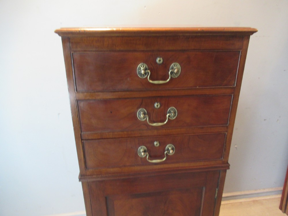 A tall, slim Victorian mahogany cabinet featuring three upper drawers with brass handles above a single lower cupboard door. View V