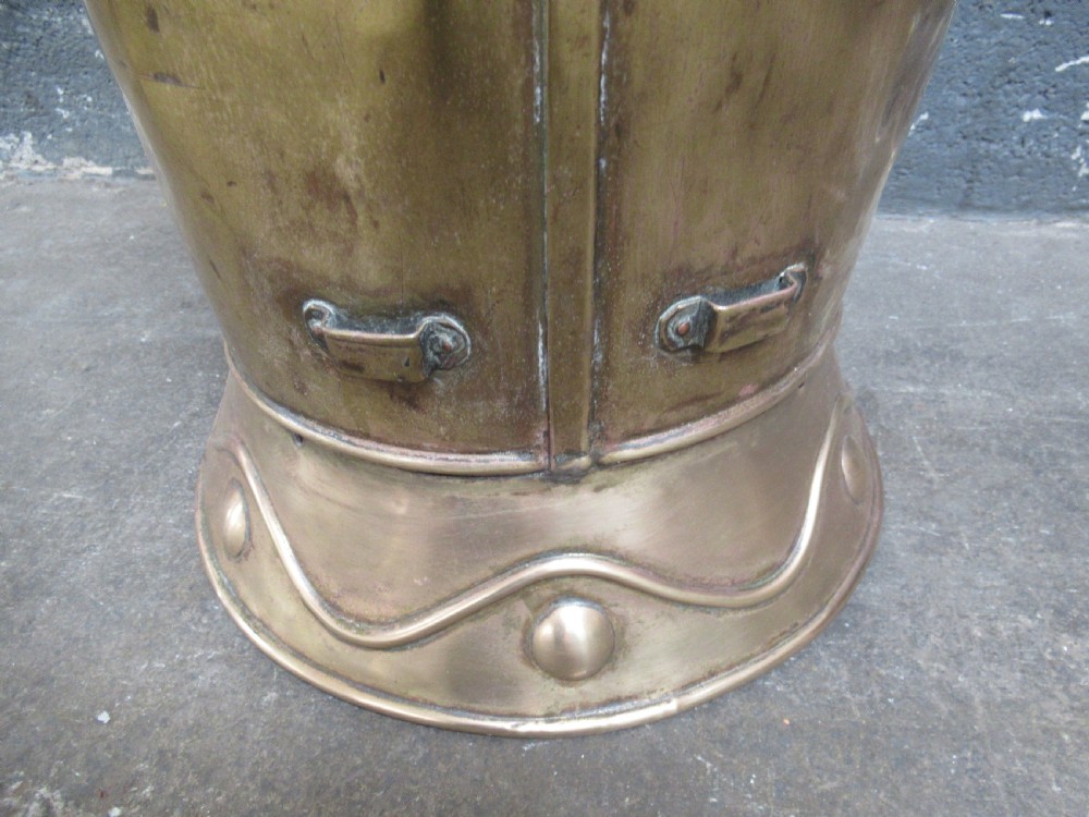 A tall, tapered brass stick stand featuring embossed relief scenes of tavern figures, decorative studding, and a raised back rim. View IX